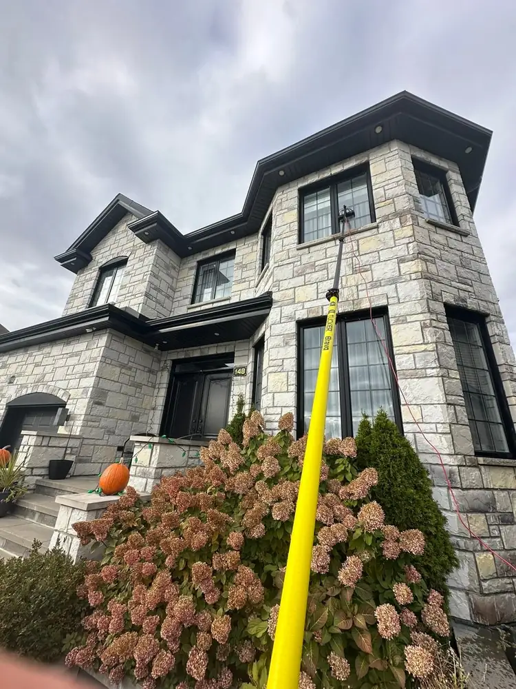 Lavage de fenêtres à l'eau déionisée sur une maison de pierre — perche télescopique